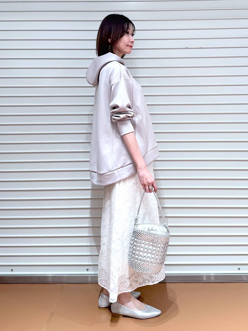 ベージュ系のパーカー、シルバー系のパンプス、ホワイト系のスカートを着用したレディースの春コーディネートの3枚目の写真