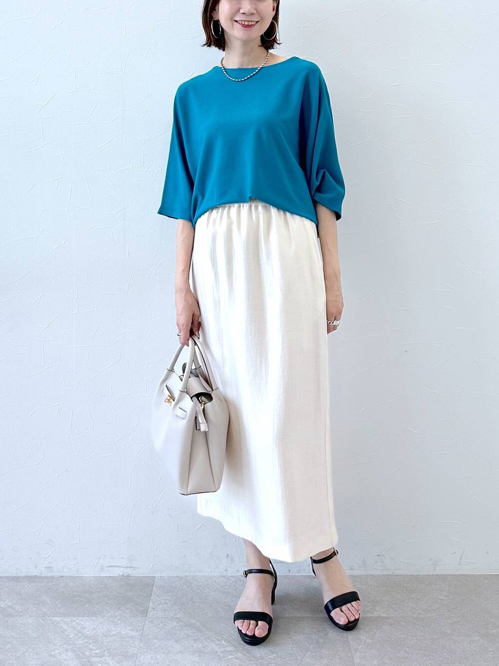 ホワイト系のスカート、ブラック系のサンダル、ブルー系のニット/セーターを着用したレディースの夏コーディネートの5枚目の写真