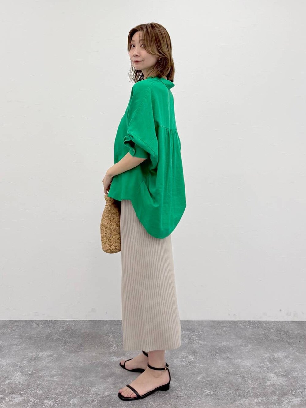 グリーン系のシャツ/ブラウス、ベージュ系のスカート、ゴールド系のネックレスを着用したレディースの春コーディネートの3枚目の写真