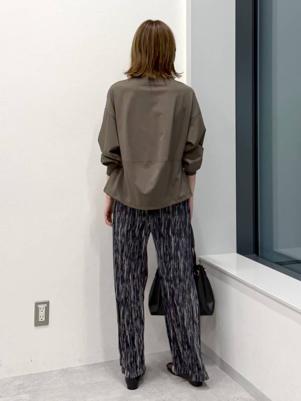 ブラック系のその他パンツ、ブラック系のトートバッグ、グリーン系のTシャツ/カットソーを着用したレディースの冬コーディネートの4枚目の写真