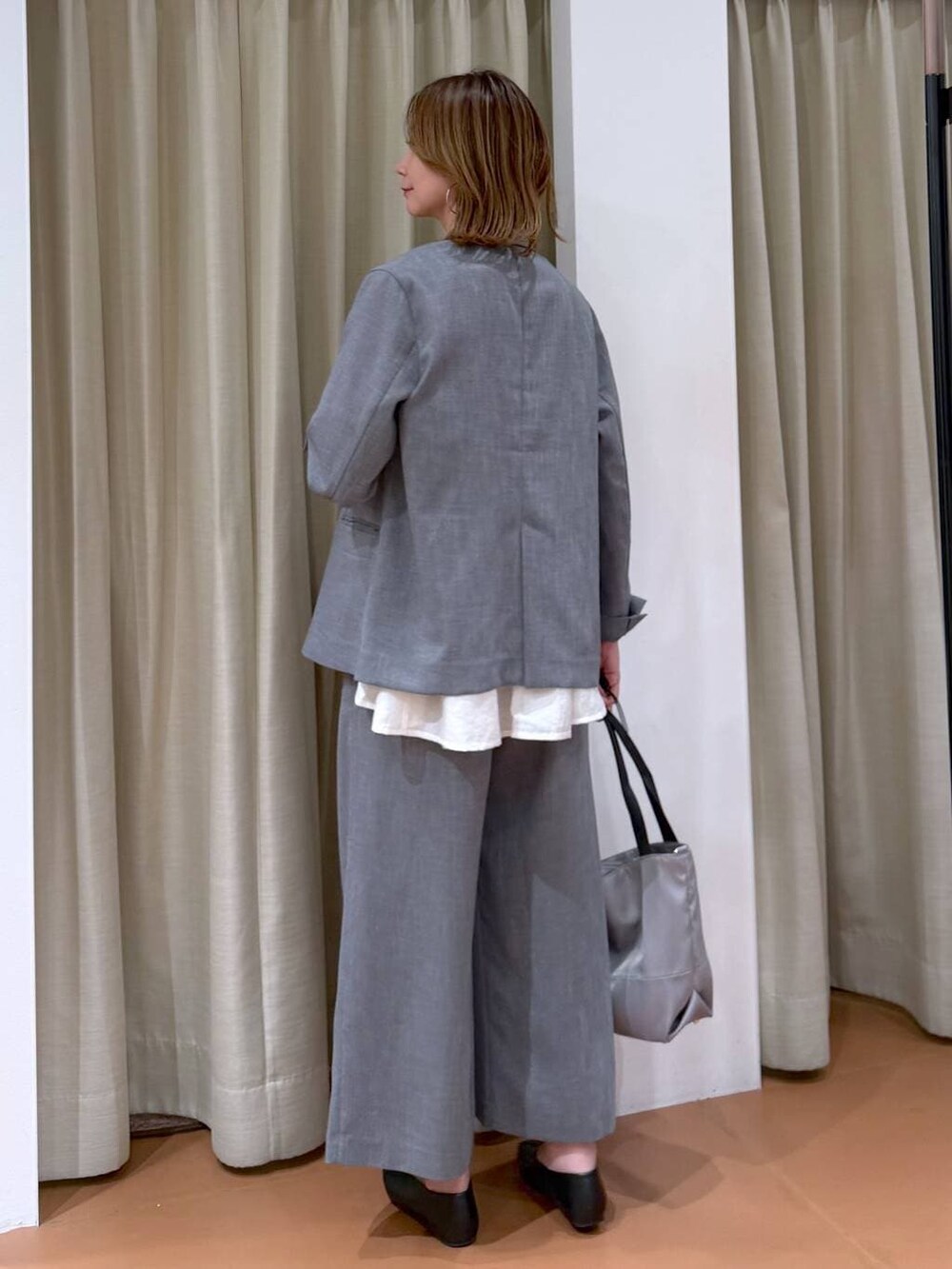 グレー系のトートバッグ、ブラック系のパンプス、ホワイト系のシャツ/ブラウスを着用したレディースの春コーディネートの4枚目の写真