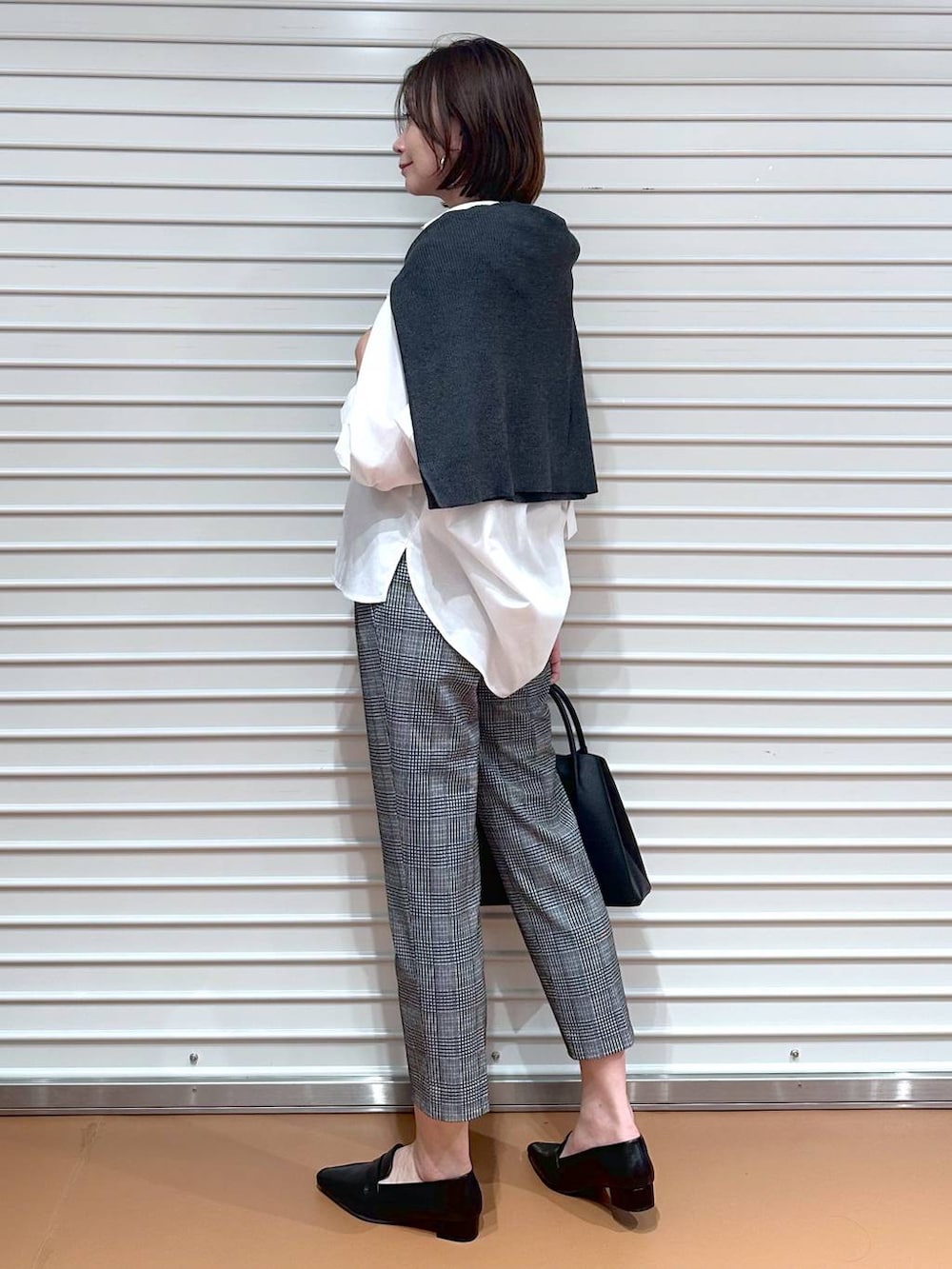 グレー系のニット/セーター、ブラック系のその他パンツ、ブラック系のハンドバッグを着用したレディースの秋コーディネートの3枚目の写真