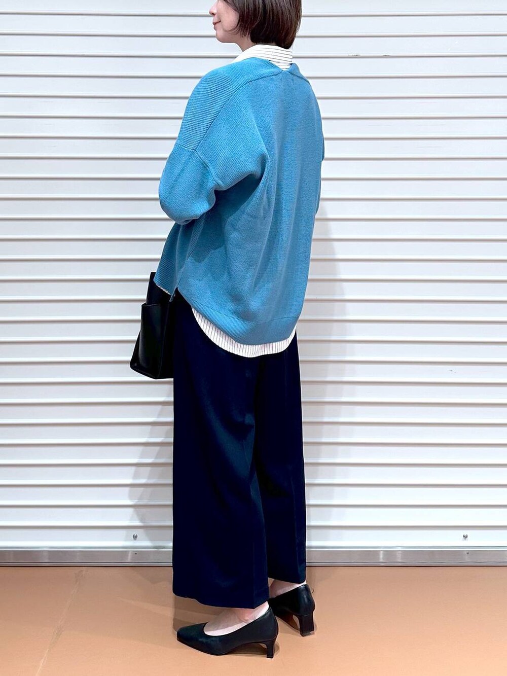 ブラック系のトートバッグ、ブルー系のニット/セーター、ホワイト系のシャツ/ブラウスを着用したレディースの春コーディネートの6枚目の写真