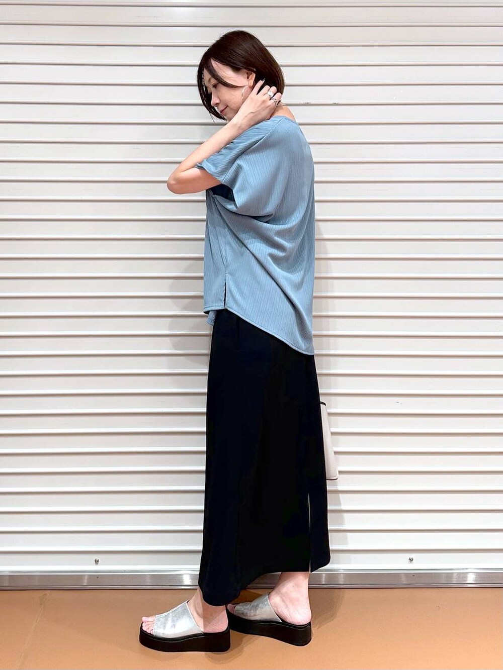 グリーン系のTシャツ/カットソー、シルバー系のサンダル、ブラック系のスカートを着用したレディースの秋コーディネートの3枚目の写真