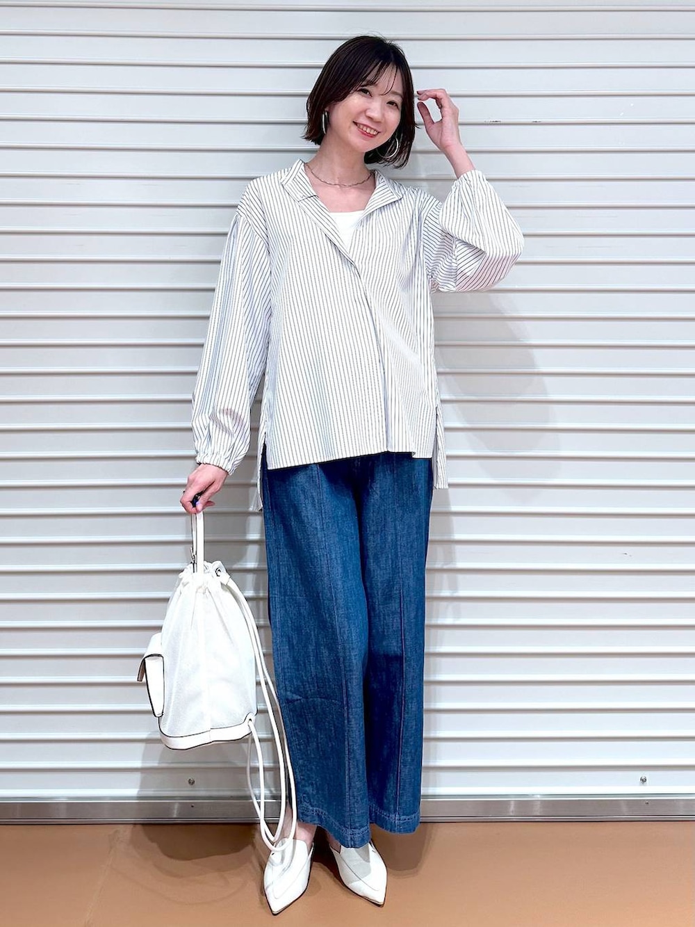 ブルー系のデニムパンツ、ホワイト系のシャツ/ブラウス、ベージュ系のマウンテンパーカーを着用したレディースの春コーディネートの4枚目の写真