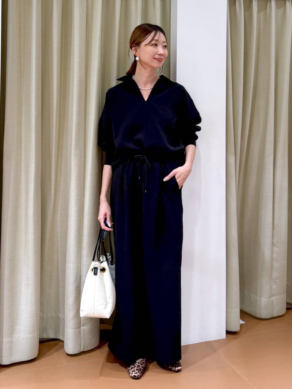 ブラウン系のパンプス、ホワイト系のトートバッグ、ブラック系のその他パンツを着用したレディースの冬コーディネートの2枚目の写真