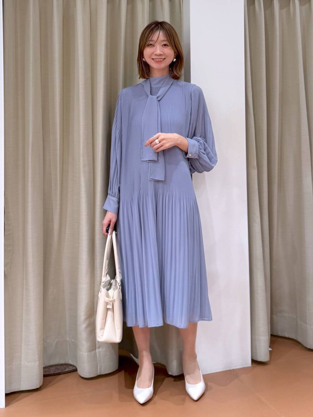 ベージュ系のパンプス、ブルー系のワンピース、ホワイト系のハンドバッグを着用したレディースの冬コーディネートの6枚目の写真