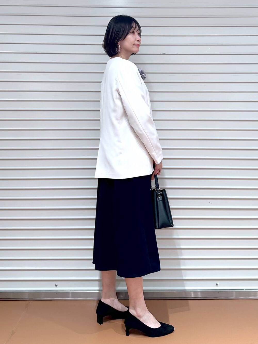 ベージュ系のノーカラージャケット、ブルー系のワンピース、ブラック系のハンドバッグを着用したレディースの冬コーディネートの3枚目の写真