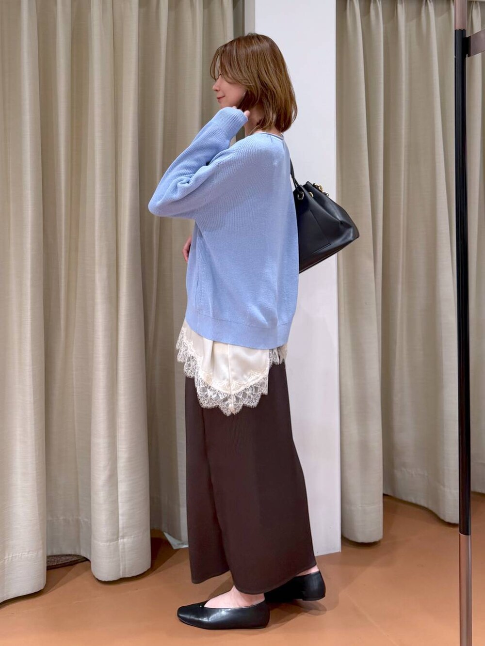 ブルー系のニット/セーター、ブラック系のパンプス、ブラウン系のスカートを着用したレディースの春コーディネートの3枚目の写真