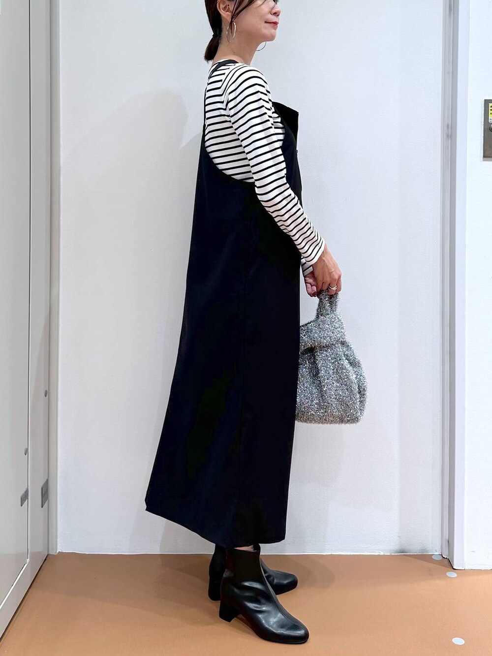 ブラック系のニット/セーター、ブラック系のブーツ、シルバー系のハンドバッグを着用したレディースの秋コーディネートの6枚目の写真