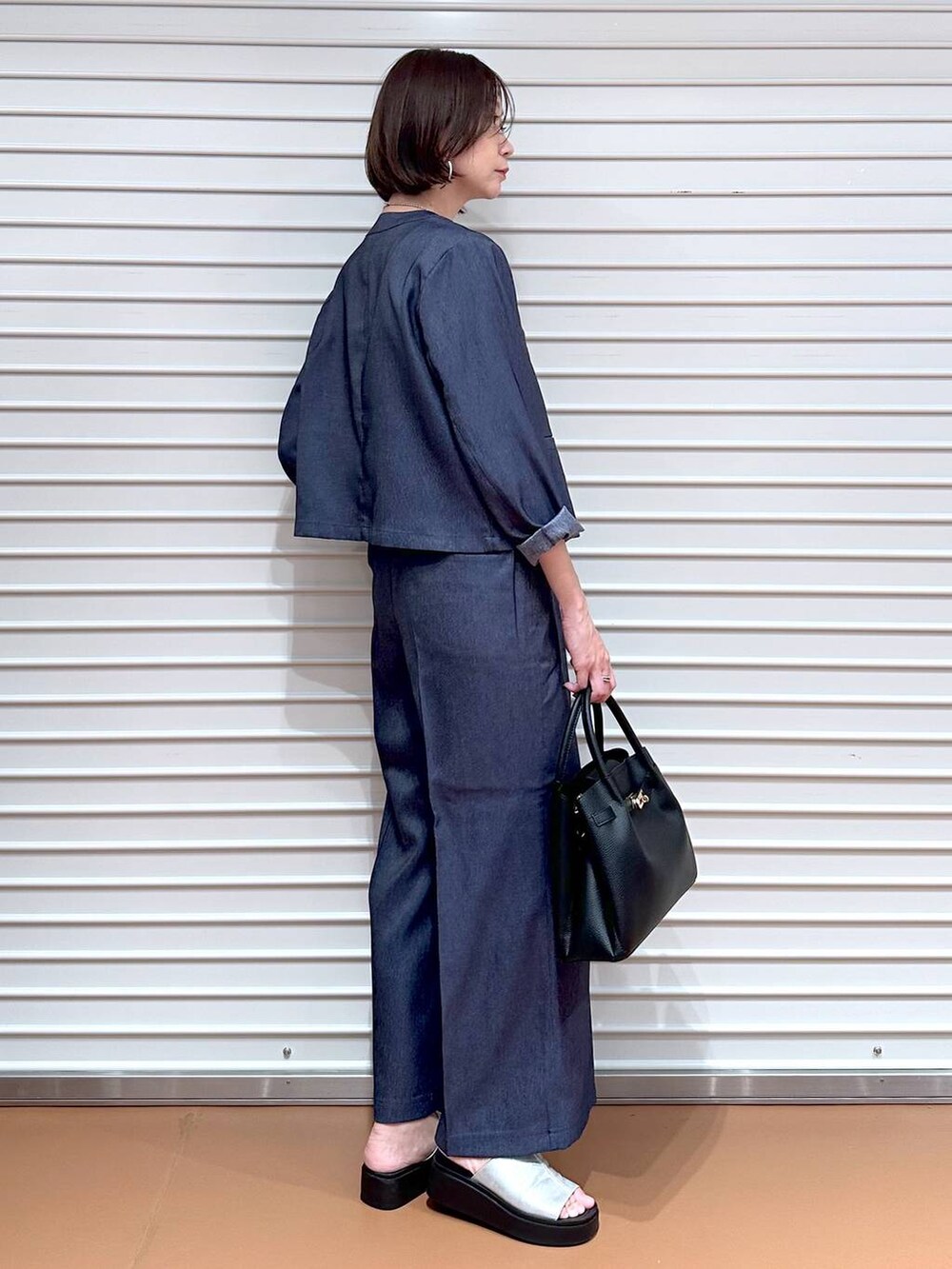 ブラック系のハンドバッグ、シルバー系のサンダル、ブラウン系のタンクトップを着用したレディースの夏コーディネートの3枚目の写真