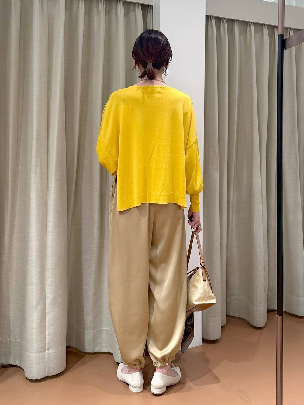 イエロー系のニット/セーター、ブラウン系のその他パンツ、グレー系のネックレスを着用したレディースの春コーディネートの5枚目の写真