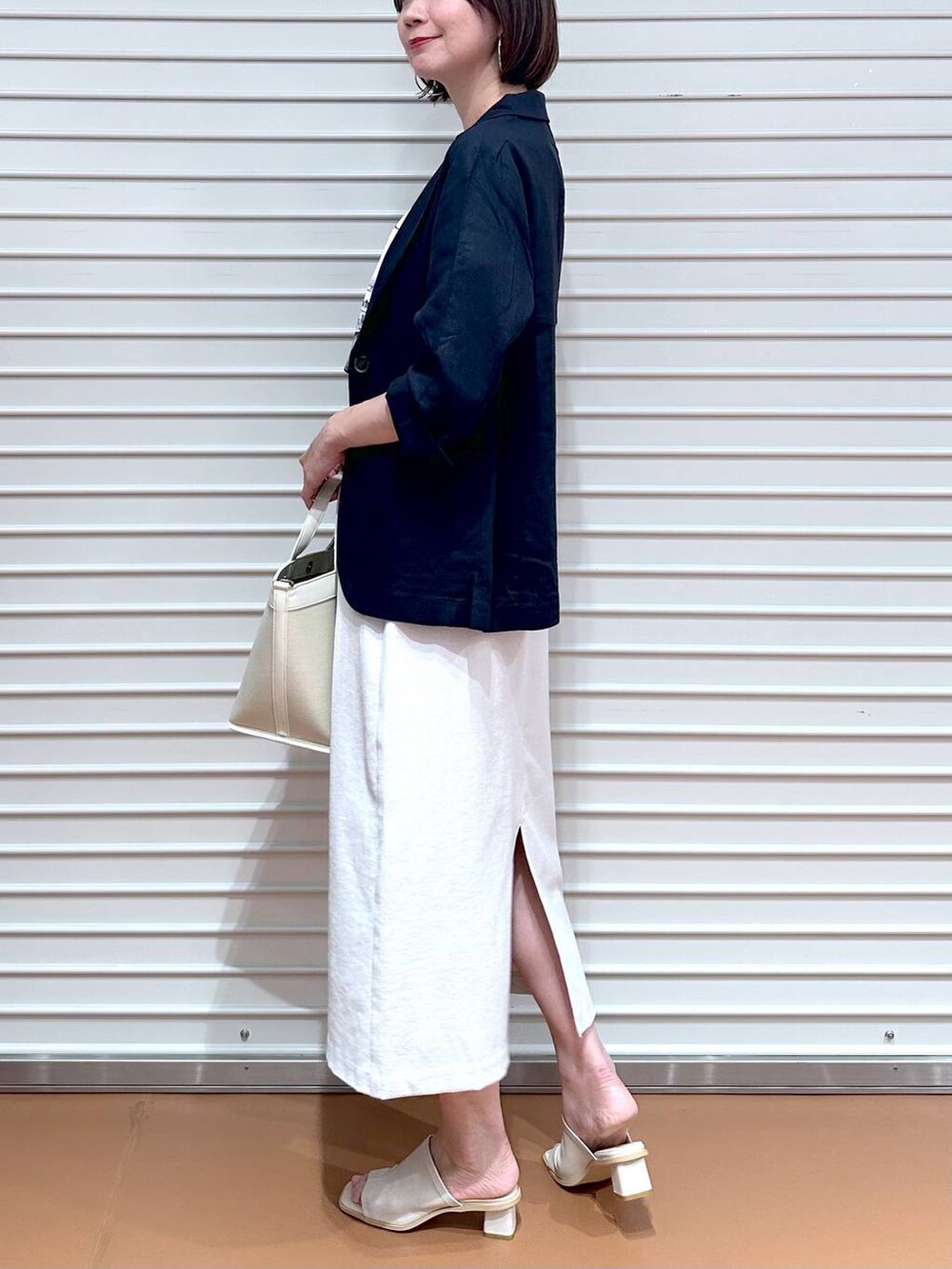 ホワイト系のサンダル、ホワイト系のトートバッグ、グレー系のスカートを着用したレディースの秋コーディネートの6枚目の写真
