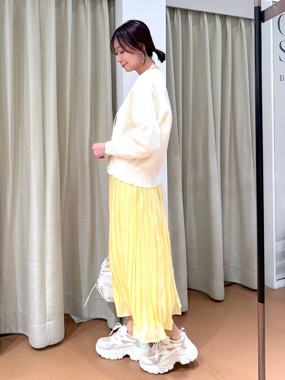 イエロー系のスカート、ホワイト系のカーディガン/ボレロ、ホワイト系のTシャツ/カットソーを着用したレディースの冬コーディネートの3枚目の写真