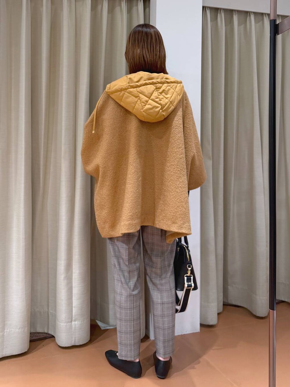 ブラック系のハンドバッグ、ブラック系のスラックス、ブラック系のパンプスを着用したレディースの冬コーディネートの4枚目の写真