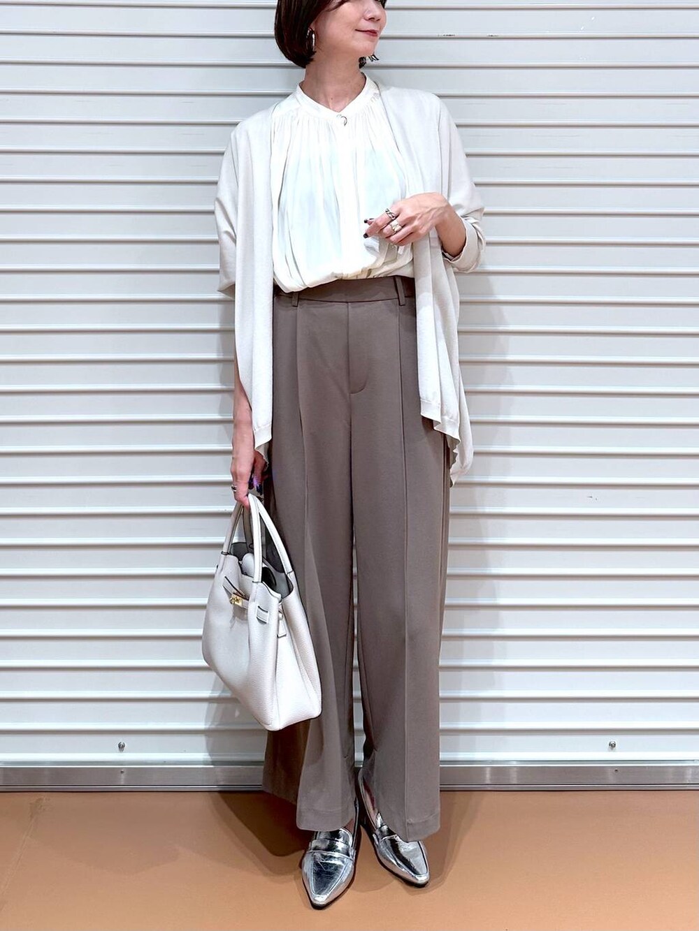 ブラウン系のその他パンツ、グレー系のカーディガン/ボレロ、グレー系のハンドバッグを着用したレディースの秋コーディネートの5枚目の写真