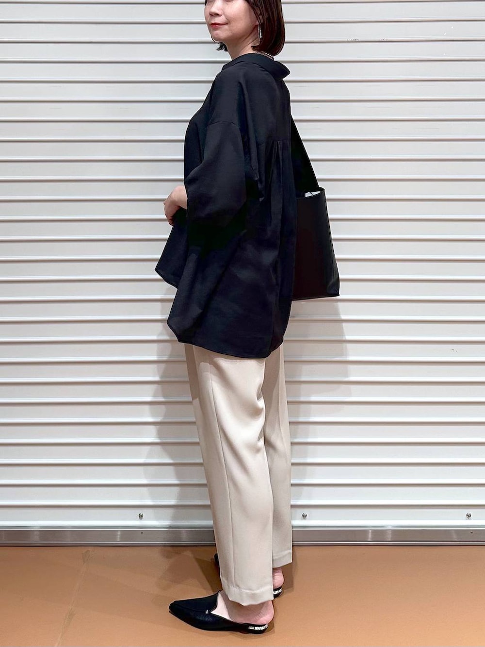 ブラック系のTシャツ/カットソー、ベージュ系のその他パンツ、ブラック系のハンドバッグを着用したレディースの春コーディネートの6枚目の写真