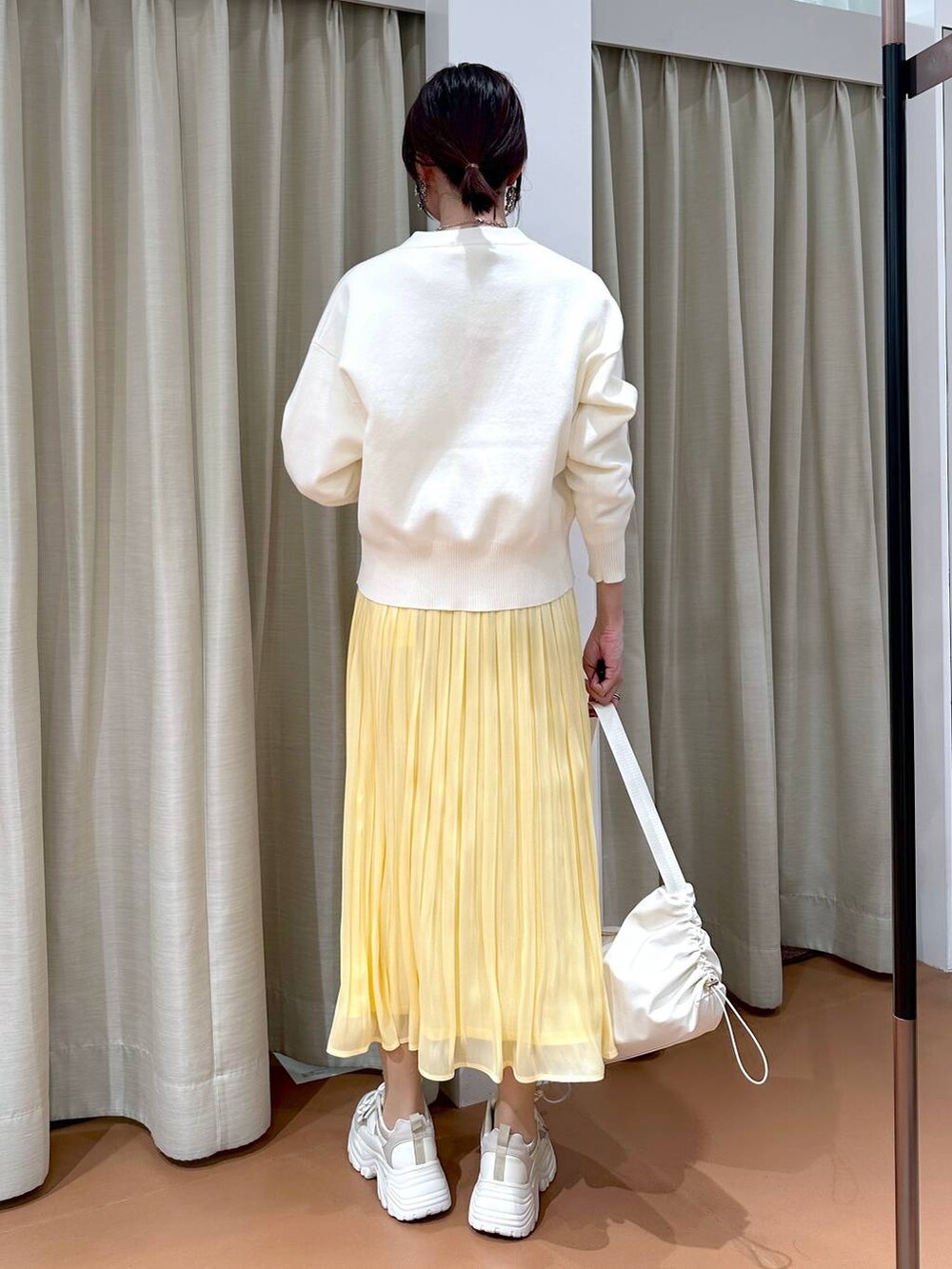 イエロー系のスカート、ホワイト系のカーディガン/ボレロ、ホワイト系のTシャツ/カットソーを着用したレディースの冬コーディネートの4枚目の写真