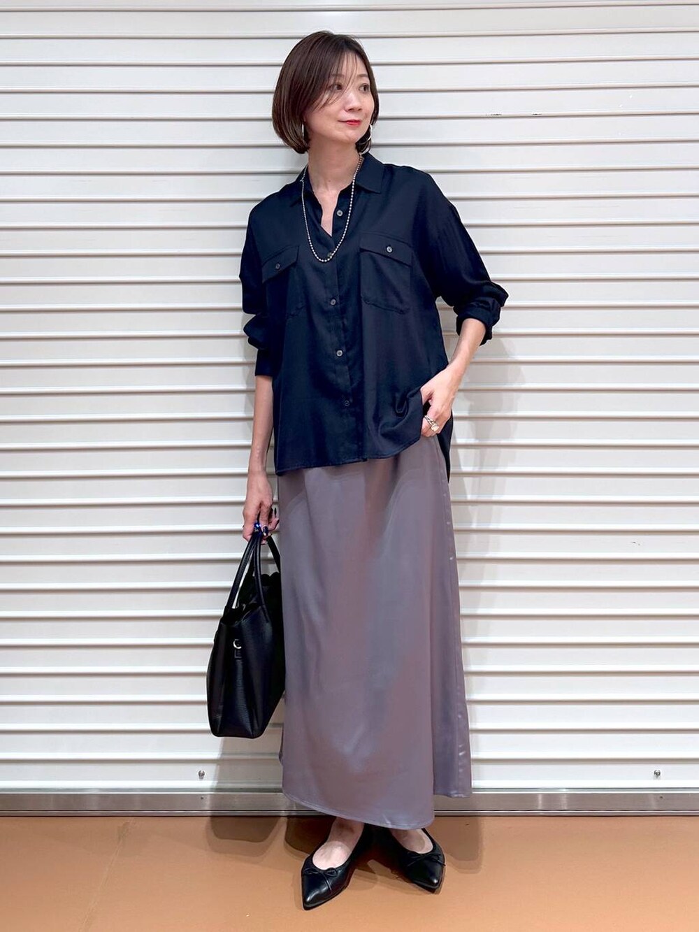 ブルー系のシャツ/ブラウス、ブラック系のパンプス、ブラック系のハンドバッグを着用したレディースの秋コーディネートの2枚目の写真