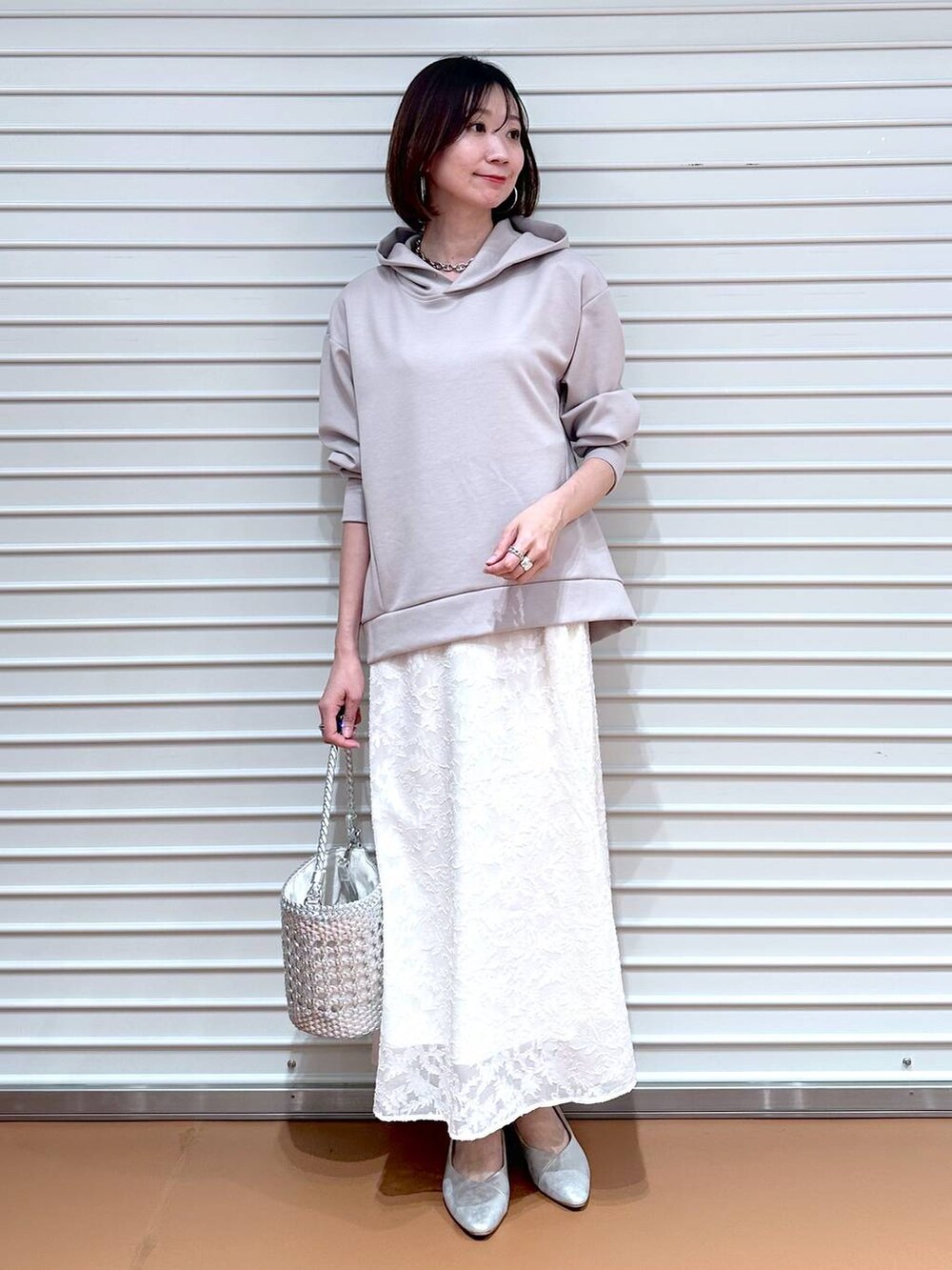 ベージュ系のパーカー、シルバー系のパンプス、ホワイト系のスカートを着用したレディースの春コーディネートの2枚目の写真