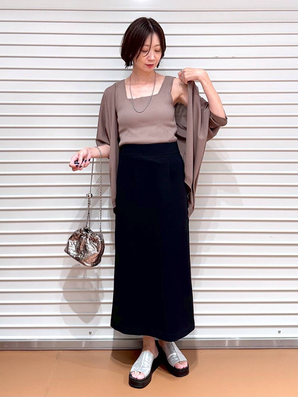 ブラック系のスカート、ブラウン系のカーディガン/ボレロ、シルバー系のサンダルを着用したレディースの夏コーディネートの2枚目の写真