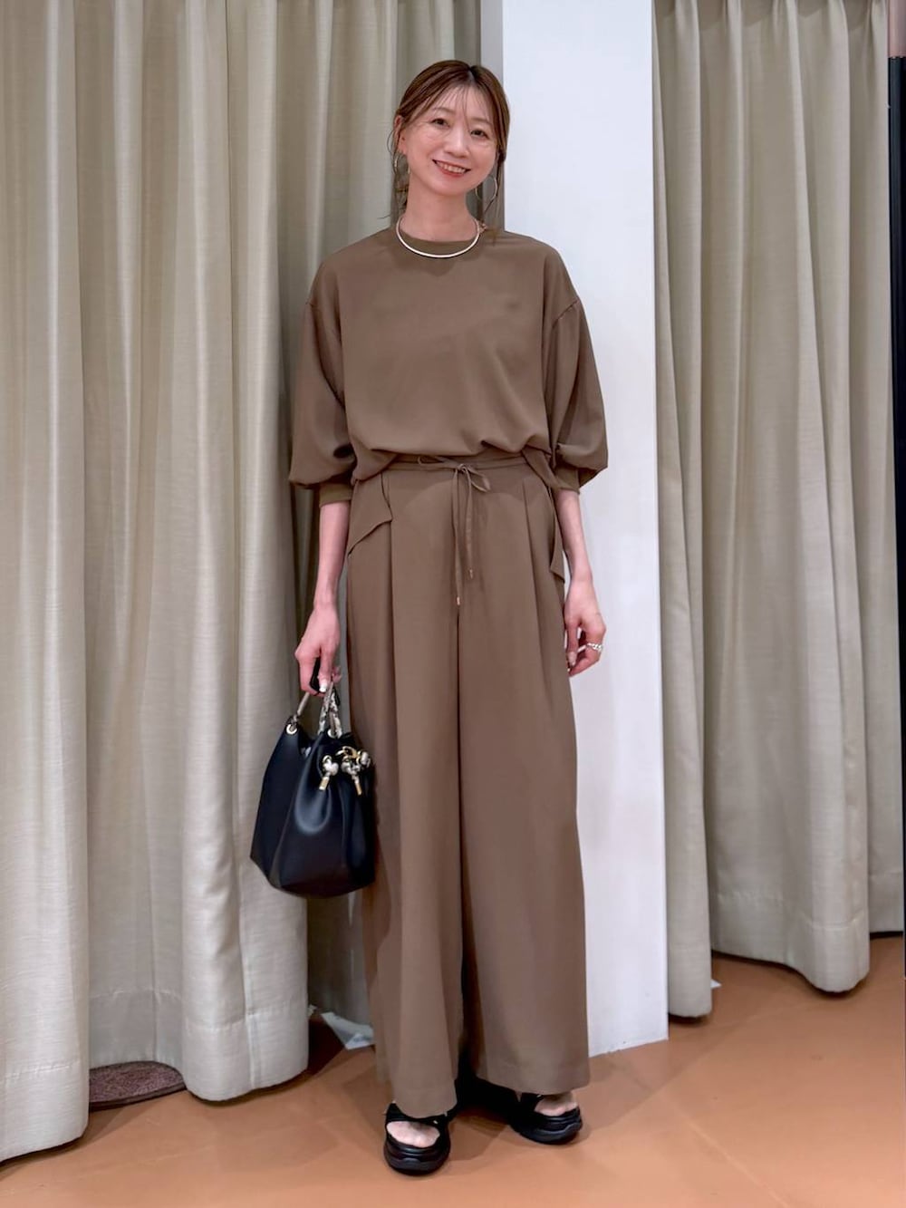 ブラック系のハンドバッグ、ブラウン系のその他パンツ、ブラウン系のシャツ/ブラウスを着用したレディースの春コーディネートの2枚目の写真