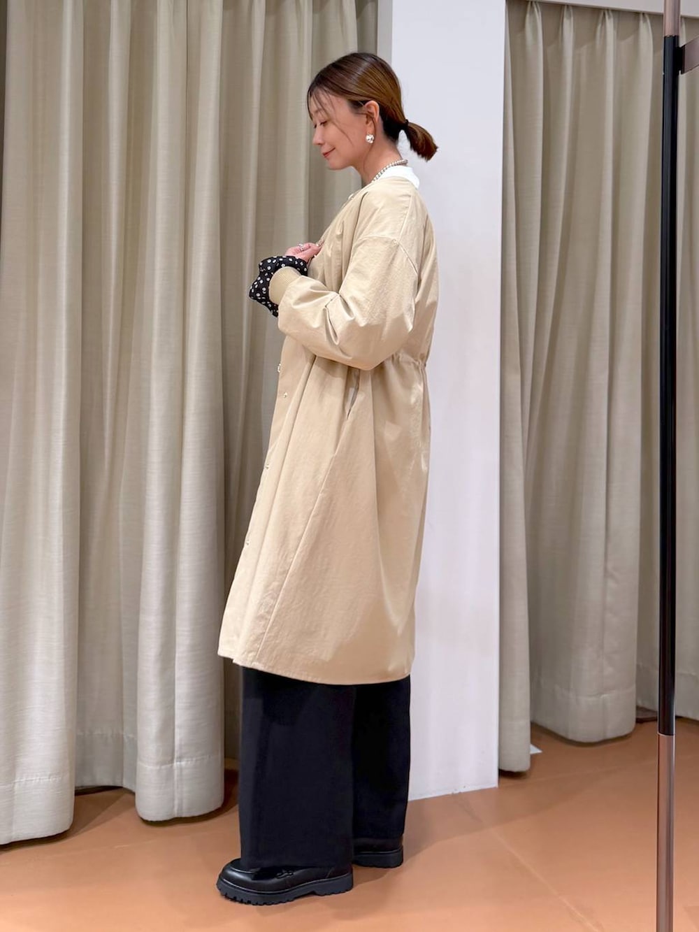 ホワイト系のハンドバッグ、ベージュ系のノーカラーコート、ブラック系のローファーを着用したレディースの冬コーディネートの3枚目の写真