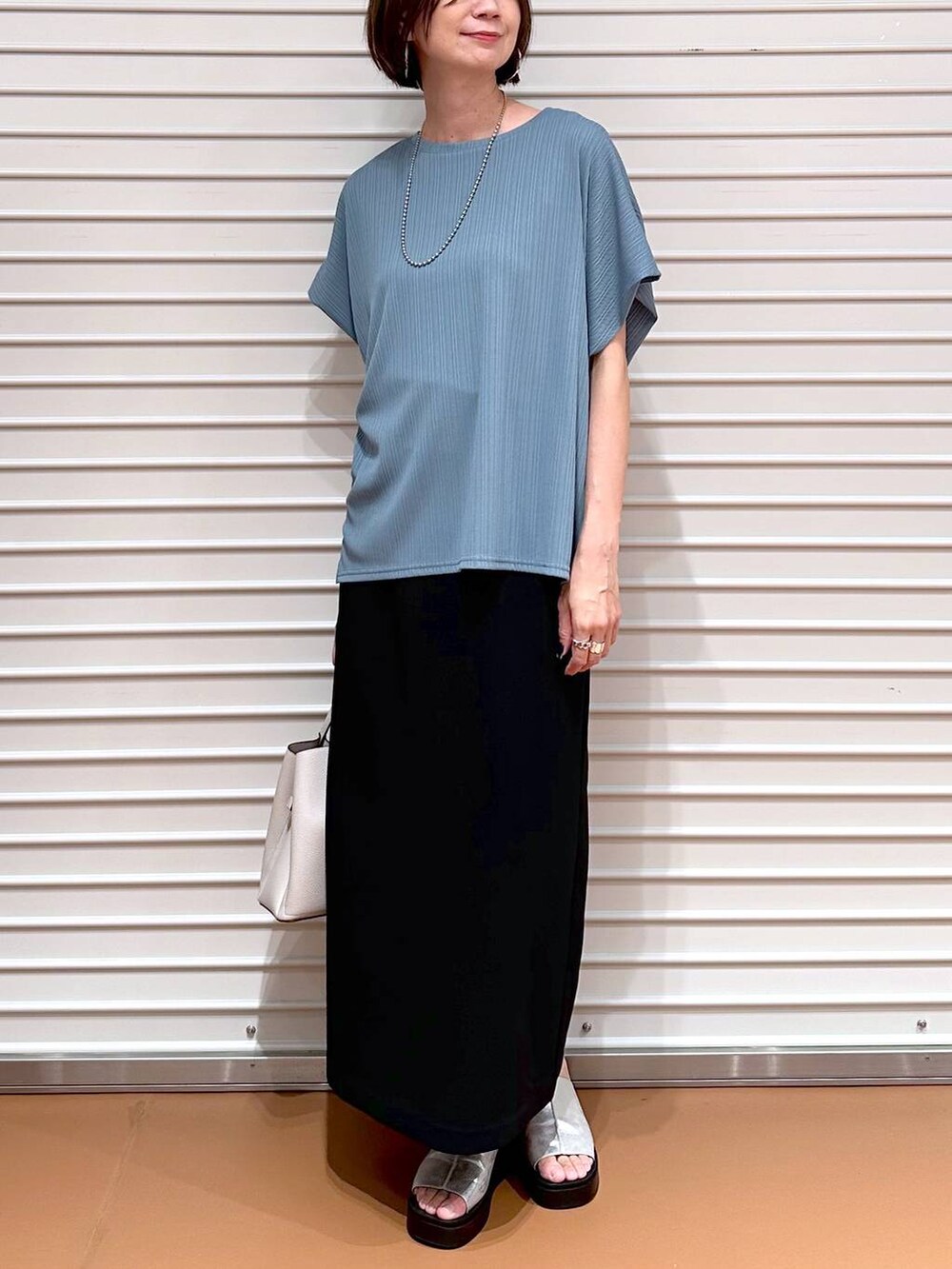 グリーン系のTシャツ/カットソー、シルバー系のサンダル、ブラック系のスカートを着用したレディースの秋コーディネートの5枚目の写真