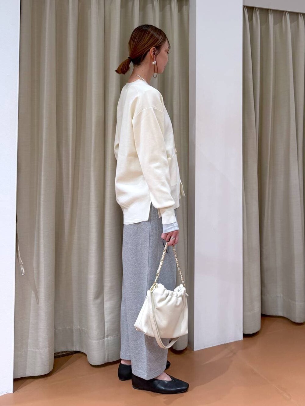 ホワイト系のカーディガン/ボレロ、ホワイト系のハンドバッグ、ブラック系のパンプスを着用したレディースの冬コーディネートの5枚目の写真