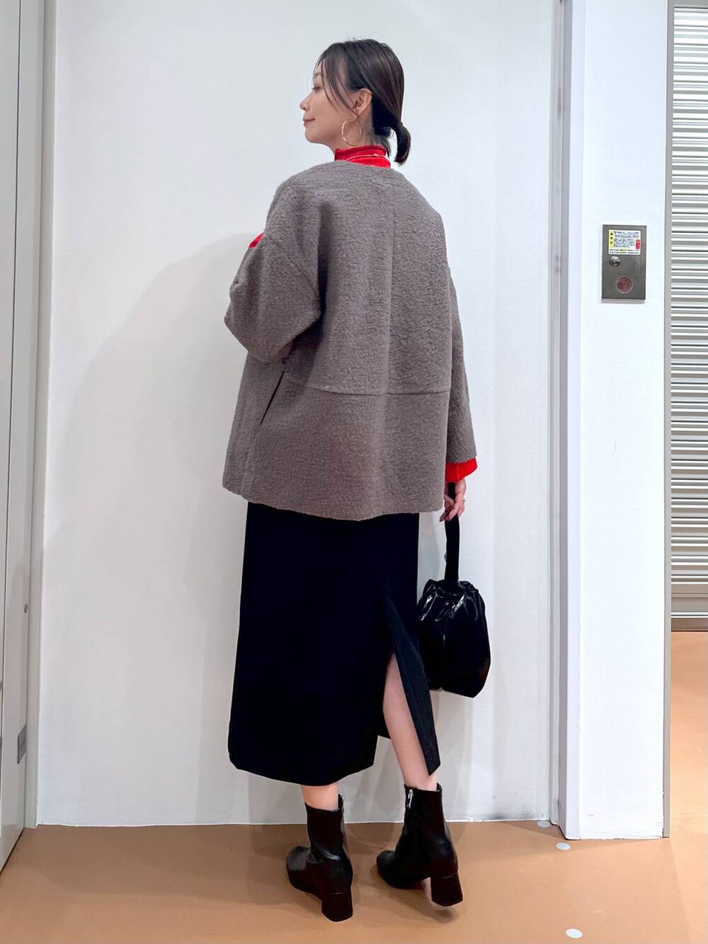 ブラック系のジャンパースカート、ブラック系のブーツ、ブラウン系のノーカラージャケットを着用したレディースの秋コーディネートの5枚目の写真