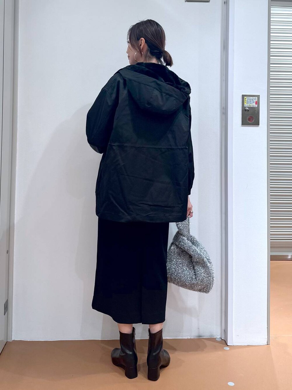 グリーン系のニット/セーター、ブラック系のジャンパースカート、ブラック系のブーツを着用したレディースの秋コーディネートの4枚目の写真