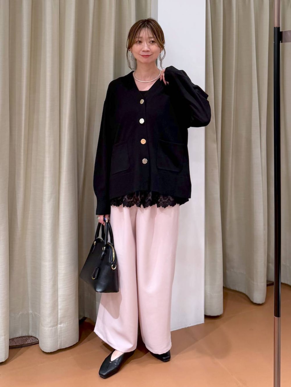 ブラック系のハンドバッグ、ブラック系のパンプス、ブラック系のタンクトップを着用したレディースの冬コーディネートの2枚目の写真