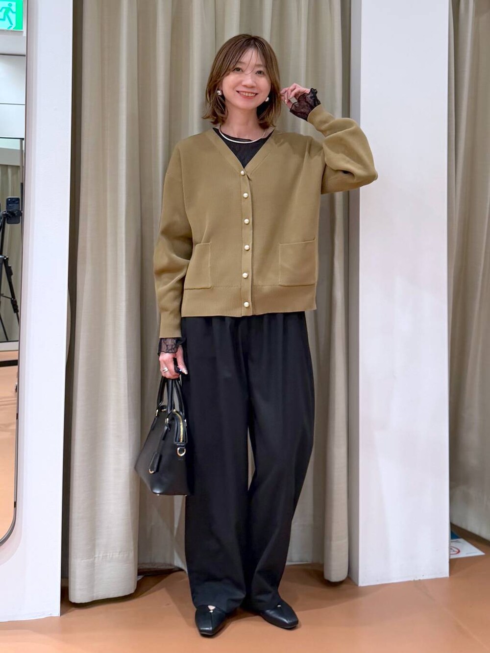 ブラック系のハンドバッグ、ブラック系のパンプス、ブラック系のTシャツ/カットソーを着用したレディースの冬コーディネートの2枚目の写真