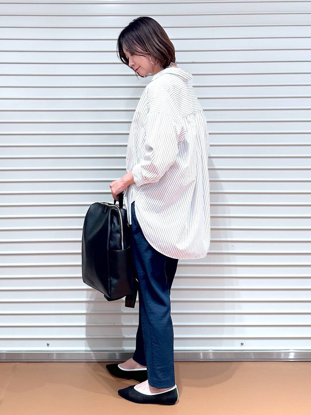 ブラック系のパンプス、ホワイト系のシャツ/ブラウス、ブラック系のバックパック/リュックを着用したレディースの春コーディネートの5枚目の写真