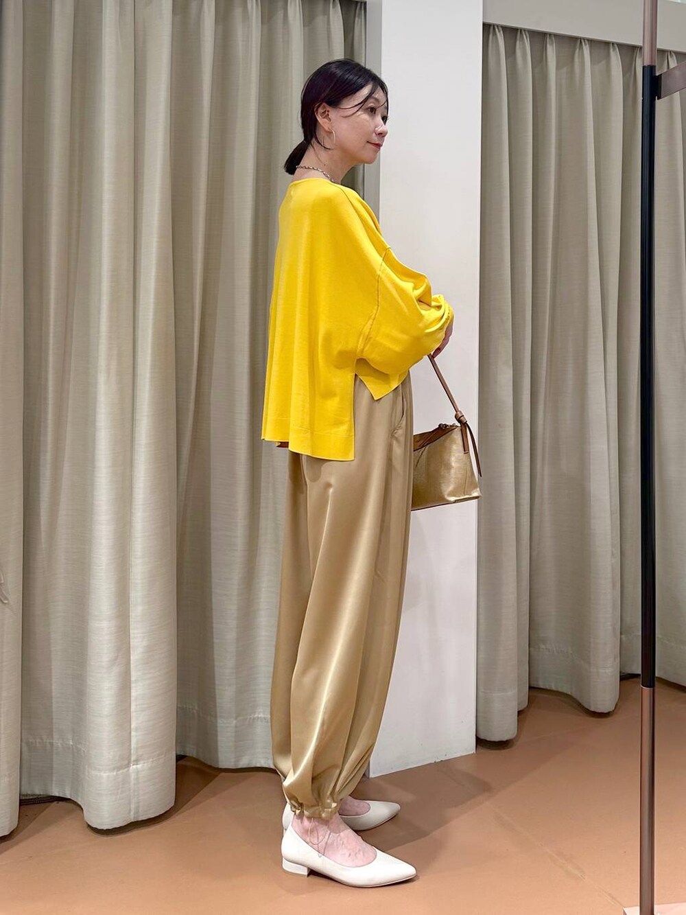 イエロー系のニット/セーター、ブラウン系のその他パンツ、グレー系のネックレスを着用したレディースの春コーディネートの6枚目の写真