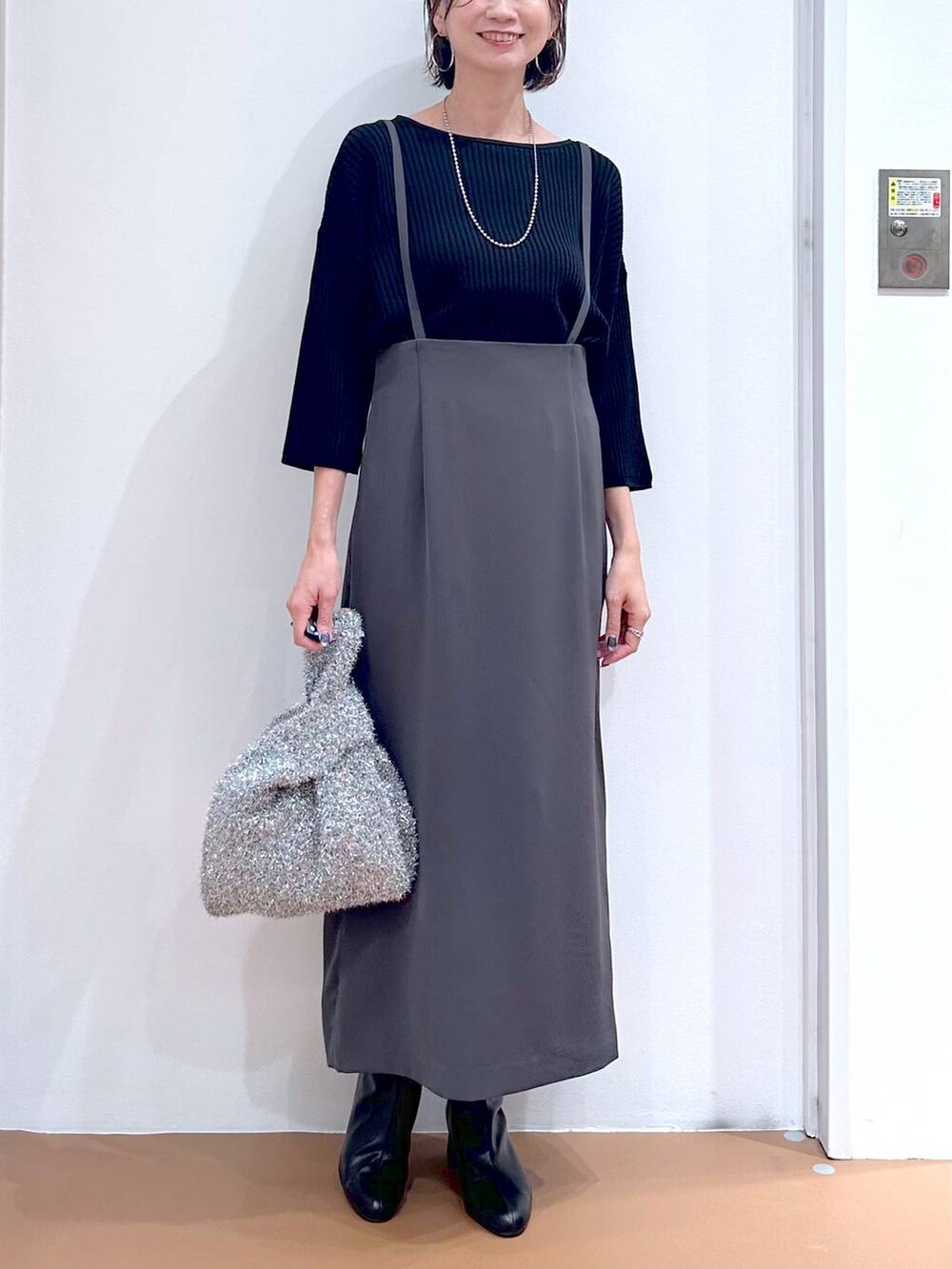 ブラック系のニット/セーター、グレー系のスカート、シルバー系のネックレスを着用したレディースの秋コーディネートの5枚目の写真