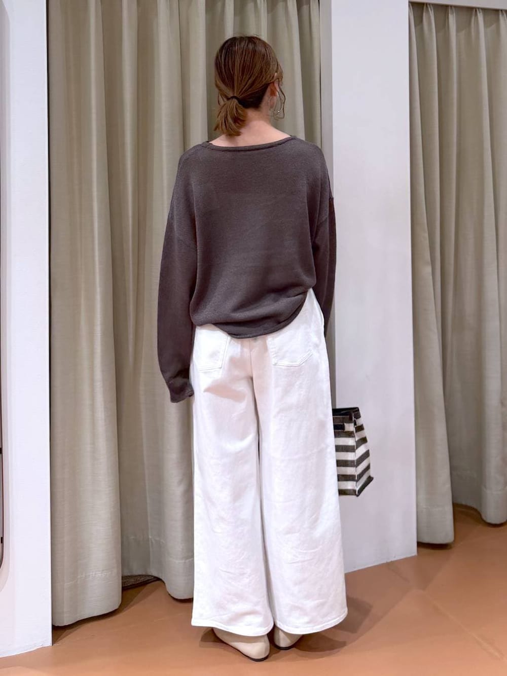 ホワイト系のパンプス、ホワイト系のデニムパンツ、ブラック系のトートバッグを着用したレディースの春コーディネートの4枚目の写真