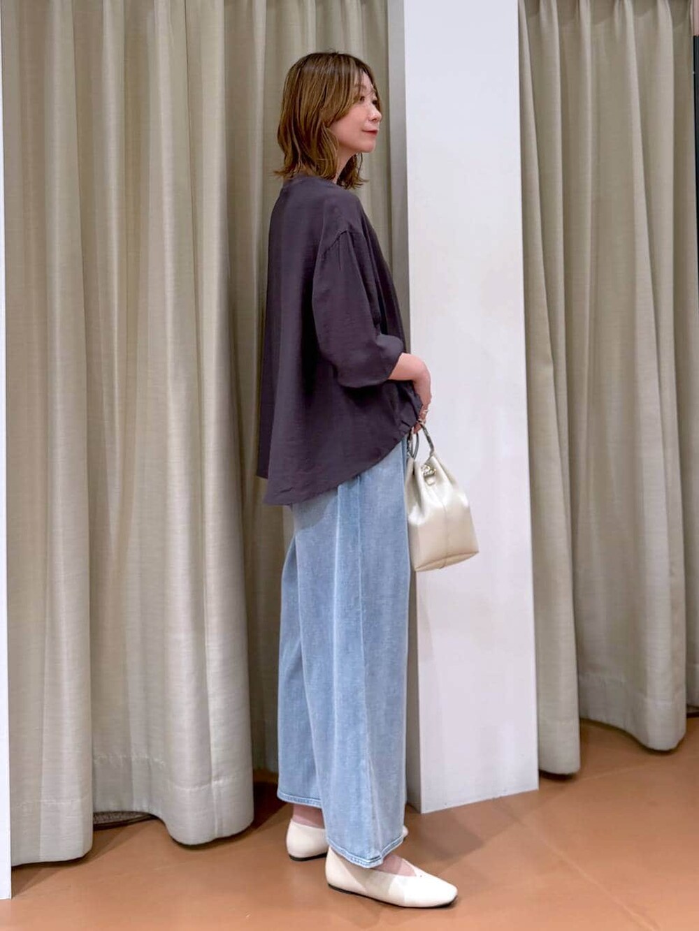 ホワイト系のパンプス、ブルー系のデニムパンツ、ホワイト系のハンドバッグを着用したレディースの春コーディネートの3枚目の写真