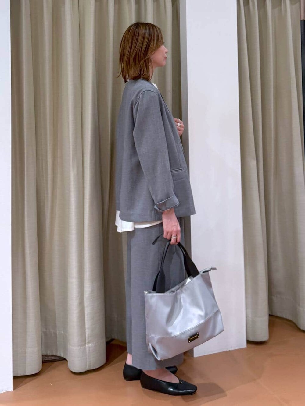 グレー系のトートバッグ、ブラック系のパンプス、ホワイト系のシャツ/ブラウスを着用したレディースの春コーディネートの5枚目の写真