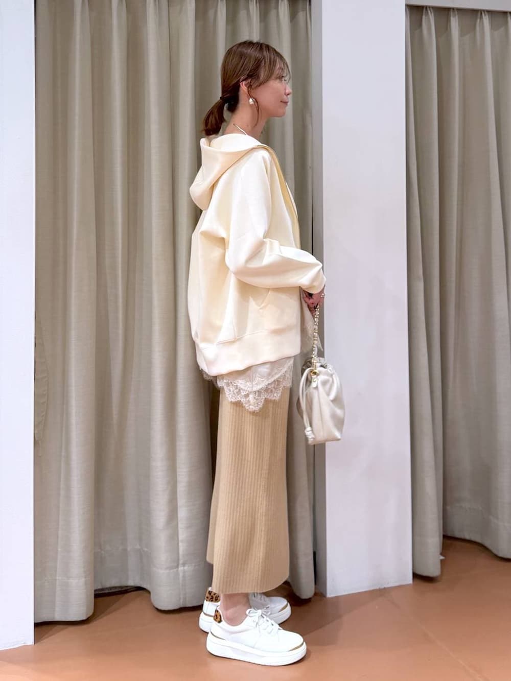 ホワイト系のハンドバッグ、ベージュ系のスカート、ホワイト系のパーカーを着用したレディースの冬コーディネートの5枚目の写真