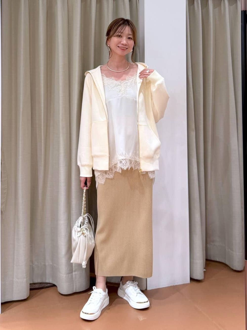 ホワイト系のハンドバッグ、ベージュ系のスカート、ホワイト系のパーカーを着用したレディースの冬コーディネートの6枚目の写真