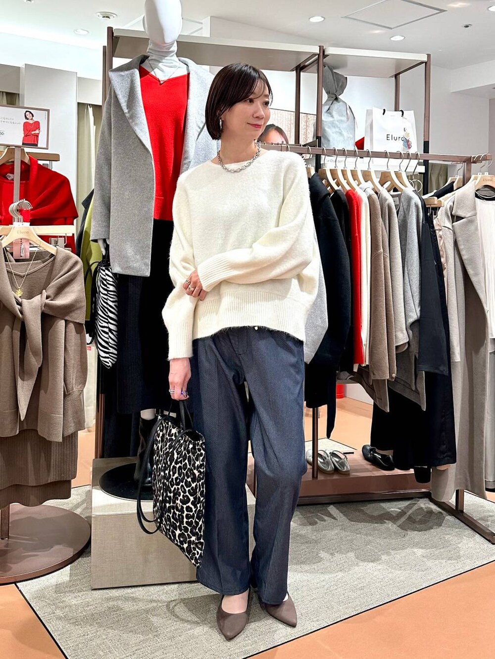 ブルー系のデニムパンツ、ホワイト系のニット/セーター、ブラウン系のパンプスを着用したレディースの冬コーディネートの2枚目の写真