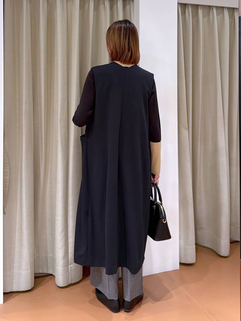 ブラック系のハンドバッグ、グレー系のその他パンツ、ブラック系のパンプスを着用したレディースの冬コーディネートの4枚目の写真