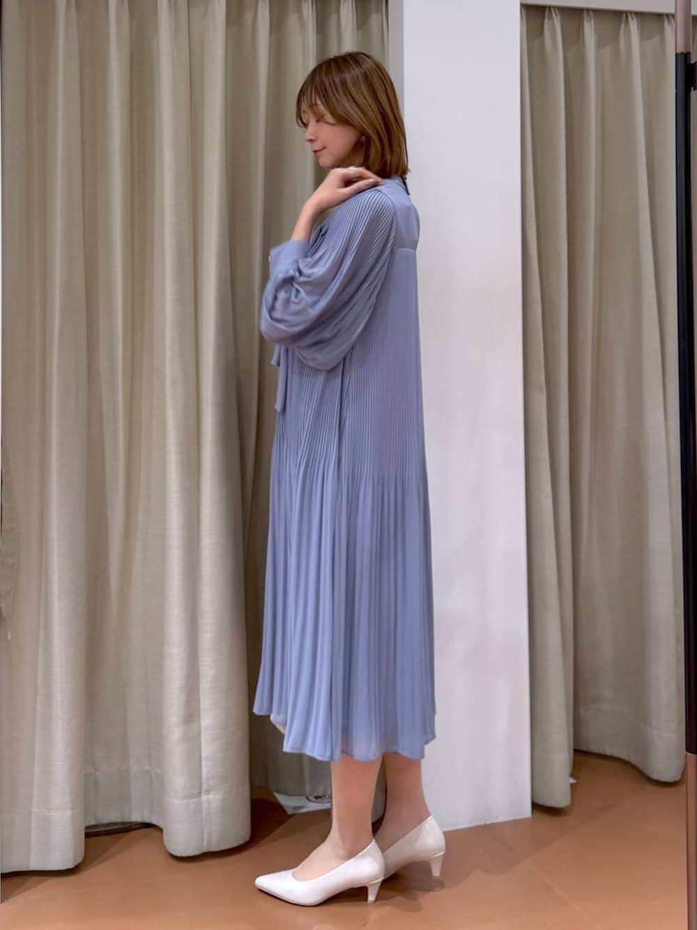 ベージュ系のパンプス、ブルー系のワンピース、ホワイト系のハンドバッグを着用したレディースの冬コーディネートの3枚目の写真