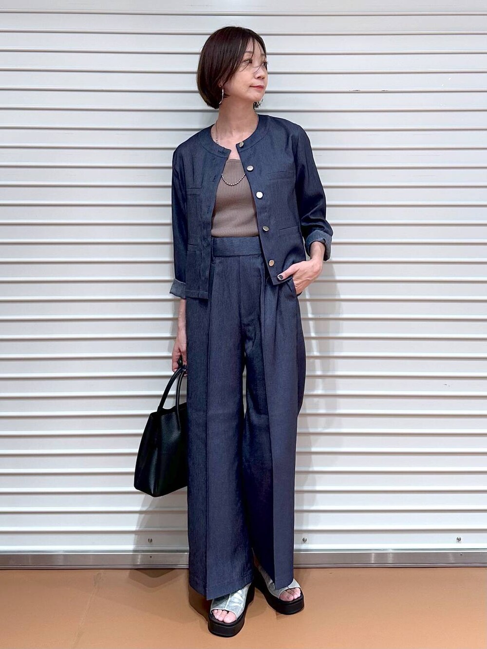 ブラック系のハンドバッグ、シルバー系のサンダル、ブラウン系のタンクトップを着用したレディースの夏コーディネートの2枚目の写真