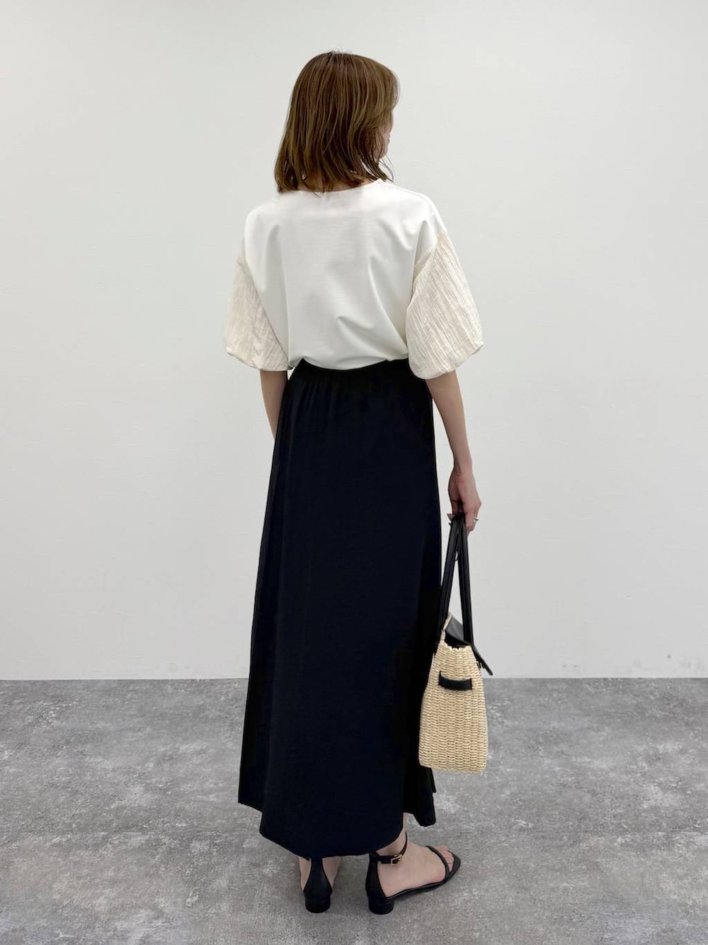 ホワイト系のTシャツ/カットソー、ブラック系のスカート、ゴールド系のネックレスを着用したレディースの春コーディネートの4枚目の写真