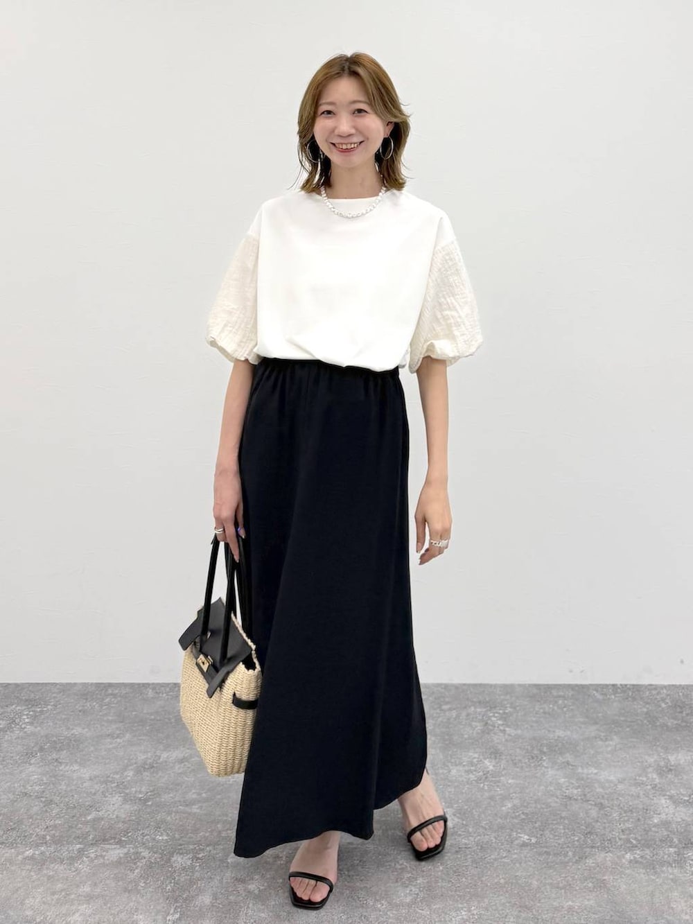 ホワイト系のTシャツ/カットソー、ブラック系のスカート、ゴールド系のネックレスを着用したレディースの春コーディネートの6枚目の写真