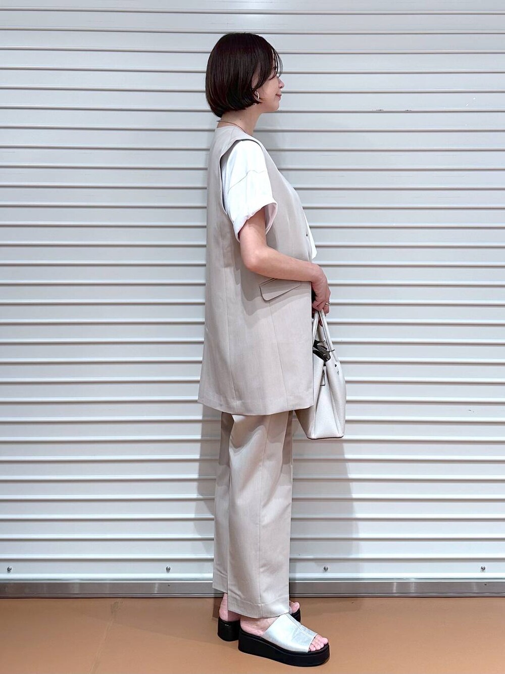 ベージュ系のベスト、シルバー系のサンダル、ホワイト系のTシャツ/カットソーを着用したレディースの夏コーディネートの3枚目の写真