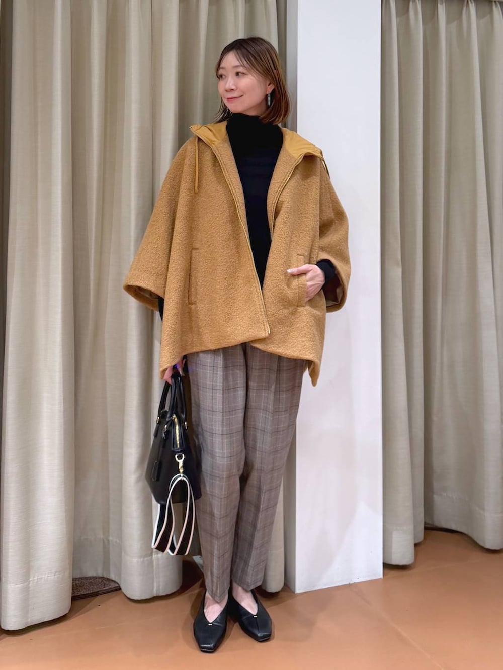 ブラック系のハンドバッグ、ブラック系のスラックス、ブラック系のパンプスを着用したレディースの冬コーディネートの2枚目の写真