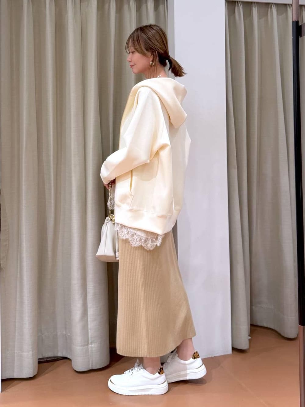ホワイト系のハンドバッグ、ベージュ系のスカート、ホワイト系のパーカーを着用したレディースの冬コーディネートの3枚目の写真